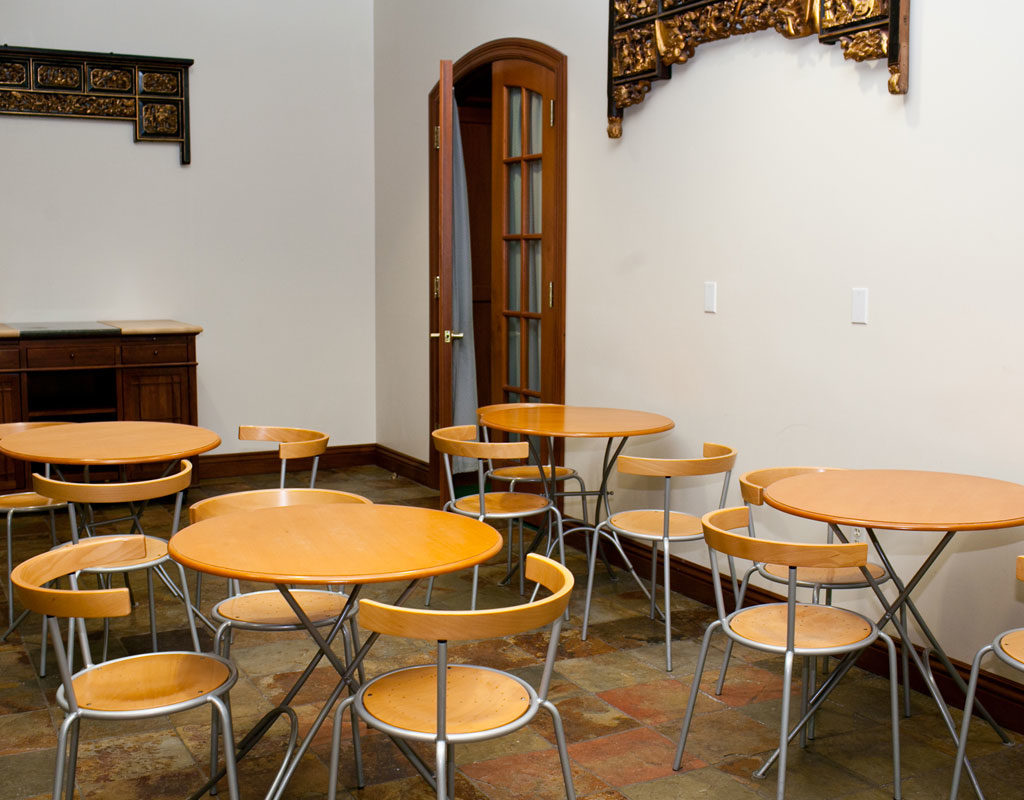 A lobby area with round tables and chairs, a doorway, and decorative artwork on the walls.